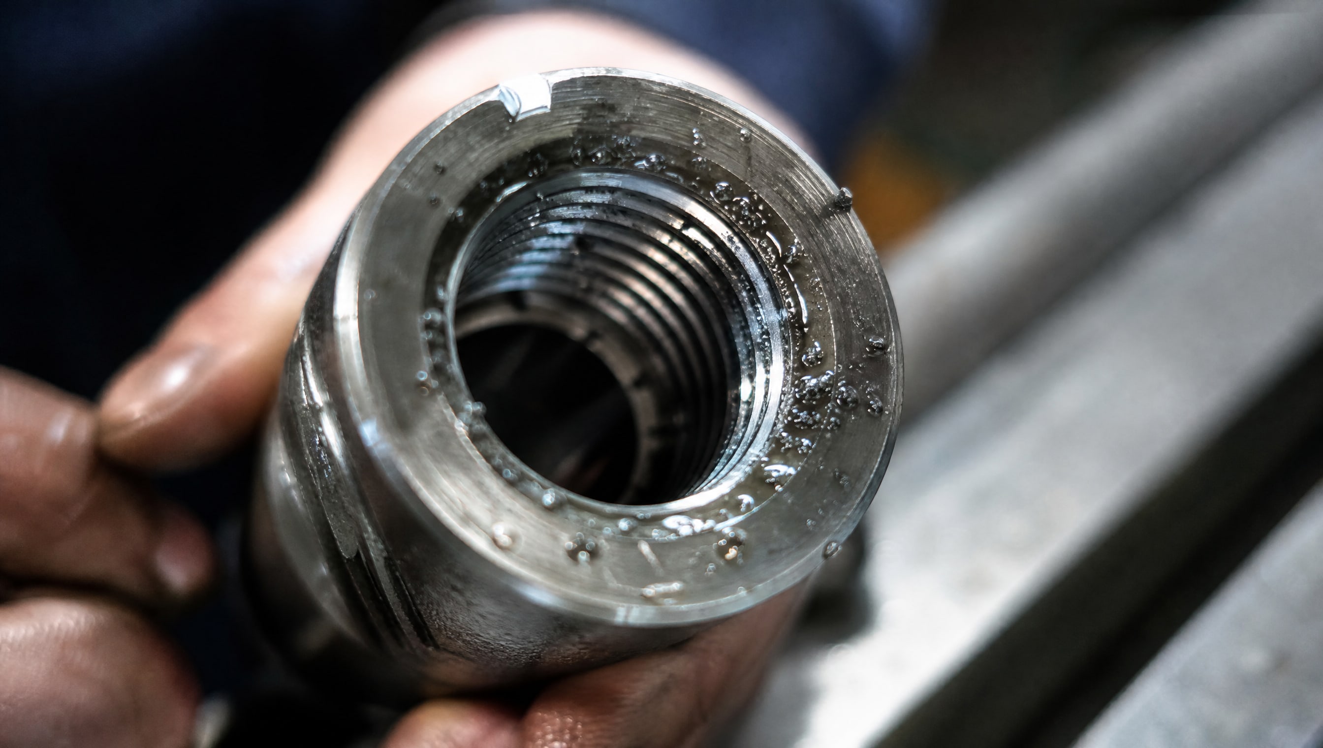 Свежая резьба с каплями эмульсии и стружкой после прохода метчика.