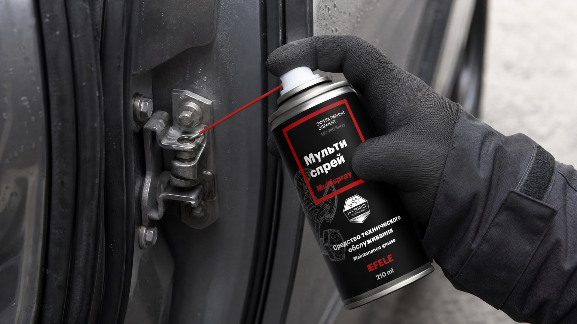 Рука в перчатке наносит EFELE MO-740 Spray, чтобы смазать дверные петли автомобиля.